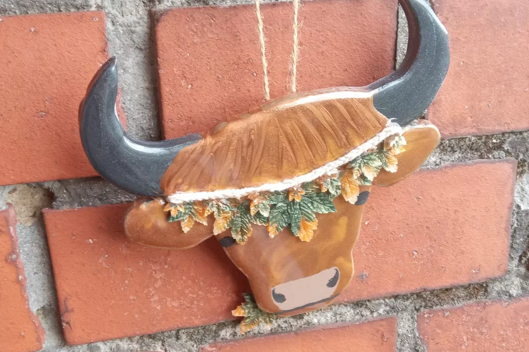 Eine dekorative Bullenkopf-Skulptur mit blühenden Pflanzen.