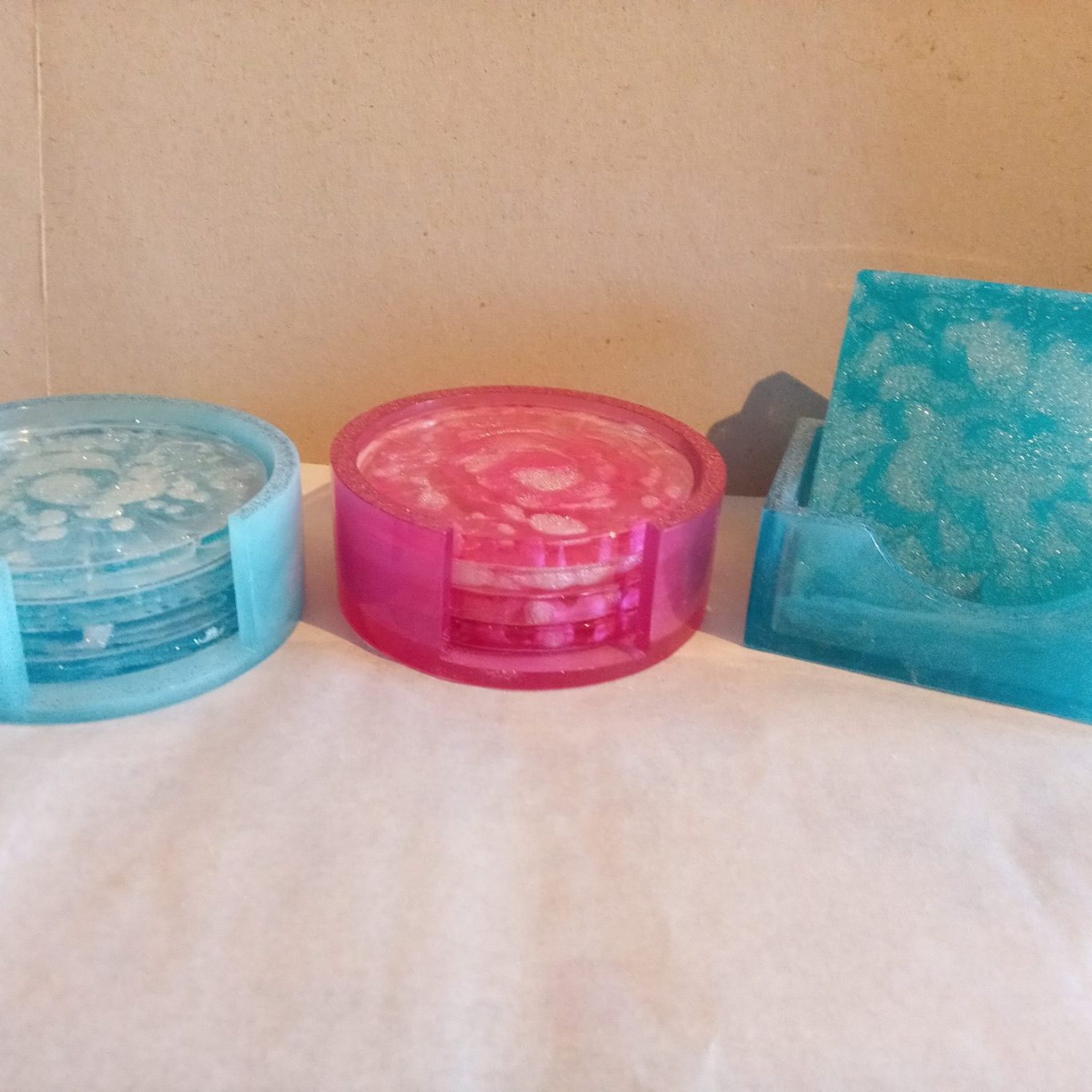Untersetzer in verschiedenen Farben: blau, pink und transparent türkis.