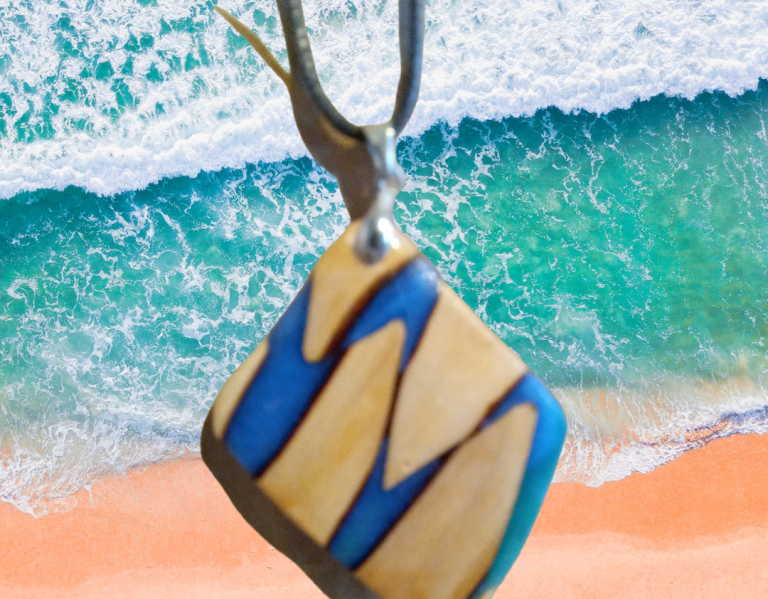 Holzanhänger mit blauem Design, vor einem Hintergrund mit Meer und Sandstrand.